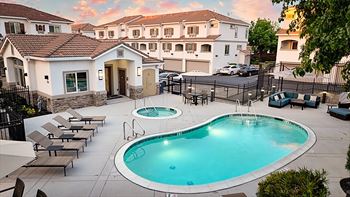 A swimming pool surrounded by lounge chairs in a residential area.